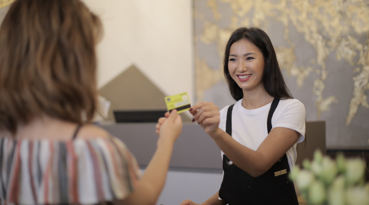 Commerçante prenant la carte de sa cliente au comptoir